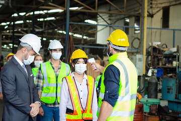 Foreman hold digital thermometer, measure temperature for screen workers with face mask, prevent against infection of Covid-19 outbreak, industrial engineers in line at manufacturing industry factory