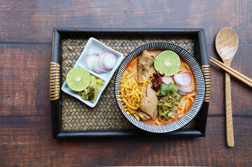 Khao Soi- Thai northern curry noodle soup with chicken, Thai traditional food of egg noodles in curry soup top with pickled cabbage, sliced onion, lime and crispy noodles at top view