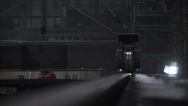 Close up of steel rails and a part of large metal industrial trolley. Clip. Interior of a dark workshop at the mining facility. 