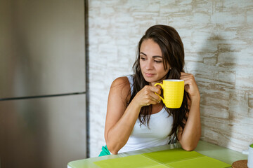 Cute woman in the kitchen with a mug of tea