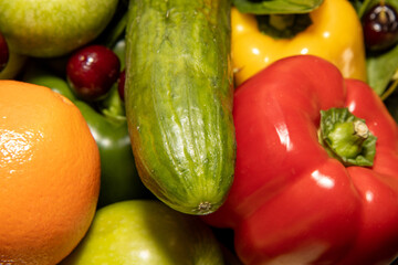 A group of fruit and vegetables including a large cucumber and red pepper