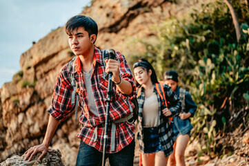 A group of hikers travel through the rocks using trekking poles to support them.Travel and adventure concept.