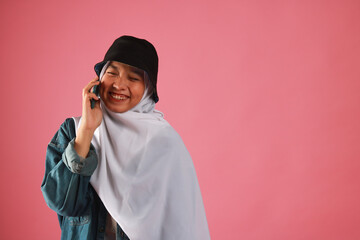 Fashion portrait of young beautiful asian muslim woman with wearing hijab isolated on pink background.