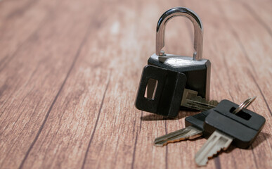 Black steel padlock with keys on a wooden background. Concept of security and tranquility.
