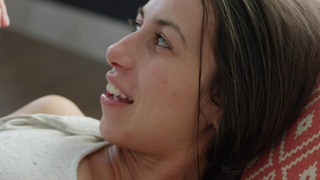 Mother and toddler son tell each other secrets while laying on couch in afternoon sun