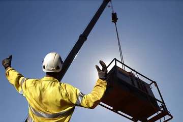 Fotobehang Rigger wearing a glove standing raising using his hands signal by moving finger slowly to directing communication with crane driver to move the boom up at construction site, Sydney, Australia    © Kings Access