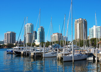 Fototapeta na wymiar Sunny, clear, blue sky morning in Saint Petersburg, Florida, showing the skyline with sailboats in the foreground with beautiful reflections on the water.