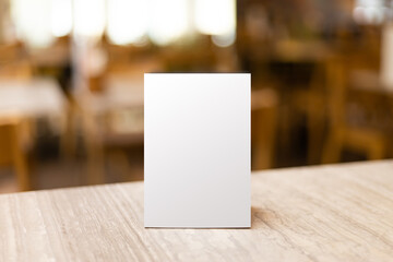 Mock up Label the blank menu frame in Bar restaurant. Stand for booklet with white sheet paper acrylic tent card on table wiht blurred background can inserting the text or picture - obrazy, fototapety, plakaty