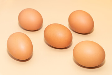 Five brown eggs on a simple background.