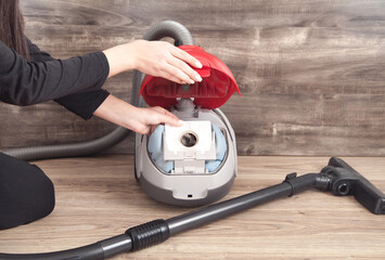 Caucasian girl opening vacuum cleaner.