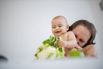 Father lovingly holding and kissing his baby daughter above a table