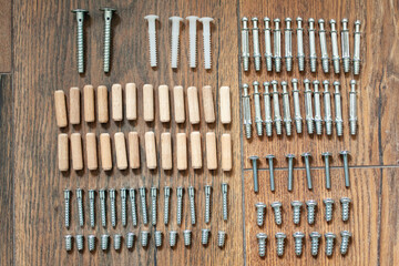 Top view arrangement group of parts (dowel, bolt, screw) for furniture assembly on wooden floor. Tools for assembling furniture. DIY concept.