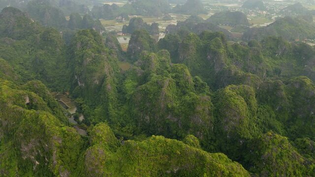 Aerial shot of beautiful limestone mountains with passes carved by a river in Ninh Binh region, a famous tourist destination in northern Vietnam. Travel to Vietnam concept