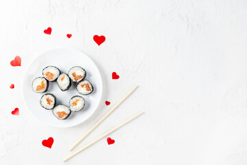 Sushi rolls for Valentine's Day with red hearts on a white plate. Horizontal orientation, copy space, top view.