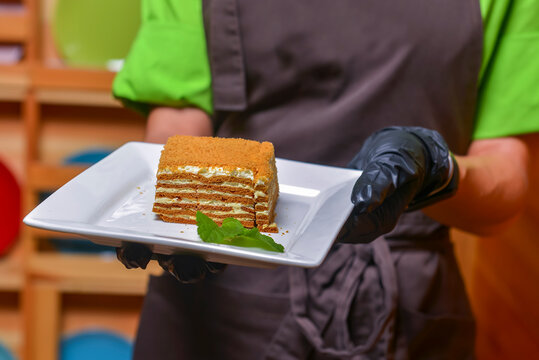 Cake Napoleon served on a white plate. Waiter serving dessert at restaurant or diner, eating out concept.