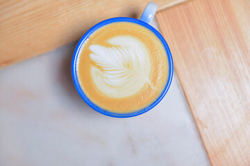 Coffee cup with coffee foam on wooden table. Latte coffee in restaurant or cafe, eating out concept, coffee concept.
