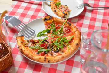 Supreme pizza on a white plate over red plaid tablecloth. Italian cuisine, Italian concept.