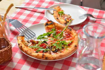 Supreme pizza on a white plate over red plaid tablecloth. Italian cuisine, Italian concept.