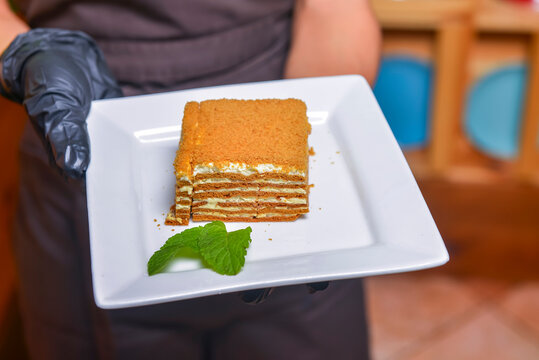 Cake Napoleon served on a white plate. Waiter serving dessert at restaurant or diner, eating out concept.