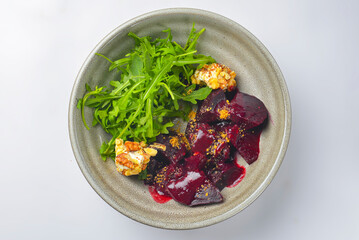 Beetroot salad with nut, cheese, arugula served in a bowl over white background. Delicious Georgian cuisine concept.