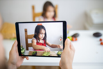 Male hands with a tablet recording a little girl cutting an avocado