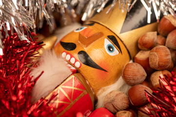 Wooden figure in the form of a soldier for chopping nuts surrounded by colored tinsel and hazelnuts...
