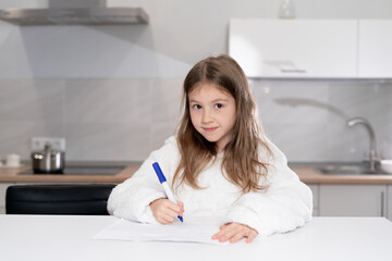 Cute little girl in headphones watching a video tutorial on drawing in an album, little preschooler draws pictures, child learns online at home,