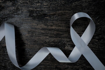 Top view of gray ribbon on dark wood background with copy space. Brain cancer tumor awareness concept.