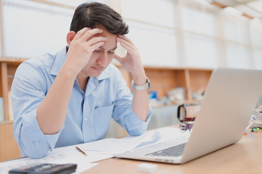 Tired businessman at workplace in office holding his headache or angry. Overworking, making mistake, stress, termination, fail, bad, sad tired or depression concept