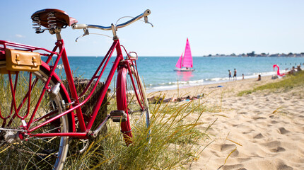 Vélo rouge en bord de mer sur une plage en France.