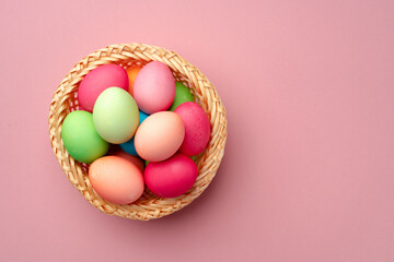 Fototapeta na wymiar Painted Easter eggs in decorative nest on pink background