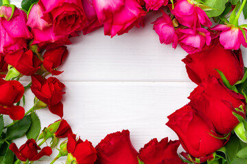 Bunch of red and pink roses on white wooden background