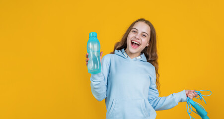 happy smiling child girl hold sport or fitness equipment of jumping rope and water bottle, health