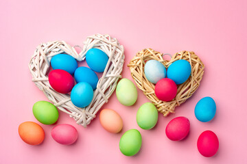 Painted Easter eggs in decorative nest on pink background