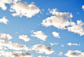 cloudscape with many illuminated clouds in blue sky