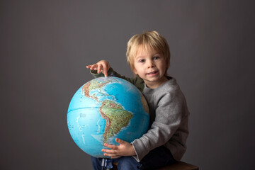 Cute toddler child, boy, hugging big globe, isolated image