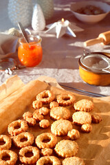 Christmas Linzer cookies filled with orange jam on cooling rack and vintage metal plate. Xmas stollen on table with natural linen tablecloth. Christmas stollen. Natural sunlight with flare, long