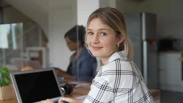 Portrait of blond woman working in open space office