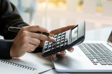 Business accounting, Businessman using calculator with budget document, computer laptop and in office, Savings, finances, and economy concept.