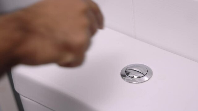 Man's hand pressing the toilet After a bowel movement
