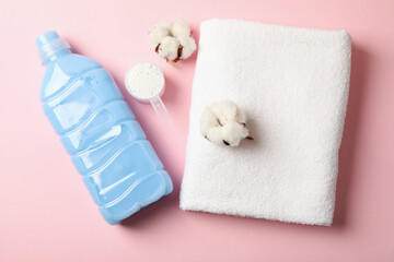 Detergent, scoop with powder, towel and cotton on pink background