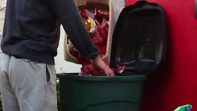 Man throws out Christmas trash. Pollution of the environment. Christmas waste, garbage, rubbish. Used wrapping paper, Christmas tree lights, pastic Christmas decorations