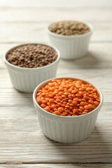 Bowls with different legumes on wooden background, close up