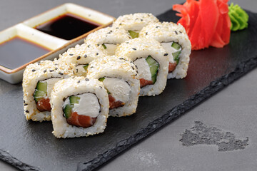 Sushi roll with salmon, philadelphia cheese and sesame on plate close up