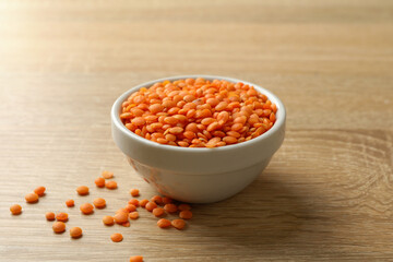 Bowl with red legumes on wooden background, close up