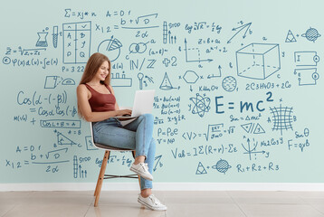 Young woman with laptop studying exact mathematical sciences. Concept of online education - obrazy, fototapety, plakaty