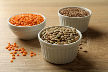 Bowls with different legumes on wooden background, close up