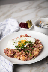 Norddeutscher Hamburger Labskaus mit Rindfleisch Corned Beef, Rote Beete, Kartoffeln, Saure Gurken, Spiegelei und Rollmops auf Teller