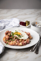 Norddeutscher Hamburger Labskaus mit Rindfleisch Corned Beef, Rote Beete, Kartoffeln, Saure Gurken, Spiegelei und Rollmops auf Teller