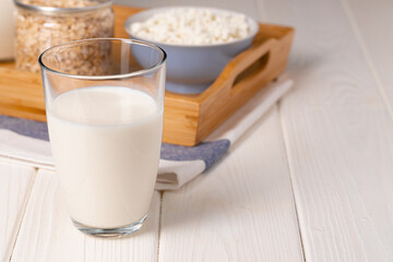 Glass of milk and oat flakes on wooden table